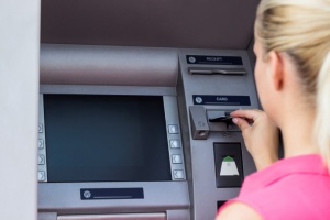 There is a lady inserting her debit card into an ATM